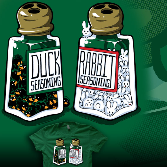 On a kelly green shirt, There are two seasoning bottles one is fill with little black ducks and has a label that says: Duck Seasoning; the other bottle is filled with little white bunnies and has a label that says: Rabbit Seasoning.
